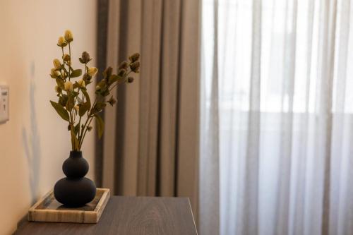 a vase with flowers in it sitting on a table at Downtown Central Apartments in Msida