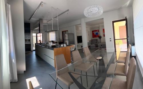 Un comedor y una cocina con una mesa de cristal y sillas. en Villa Oasi Bonita a Mondello, en Palermo