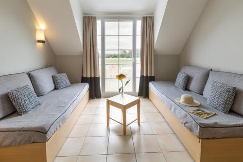 a living room with two couches and a window at Résidence Pierre & Vacances le Green Beach in Port-en-Bessin-Huppain