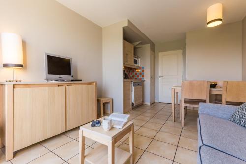 a living room with a couch and a tv and a table at Résidence Pierre & Vacances le Green Beach in Port-en-Bessin-Huppain