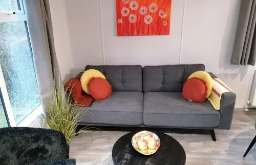 a living room with a gray couch with red and yellow pillows at Vakantiepark de Zeeuwse Parel - Summerdream in Sint Maartensdijk
