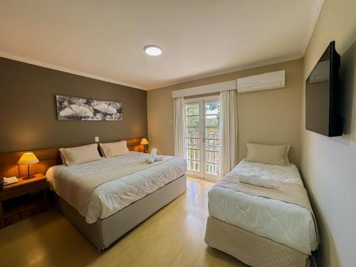 a bedroom with two beds and a flat screen tv at Pousada Nacional Inn Campos do Jordão in Campos do Jordão