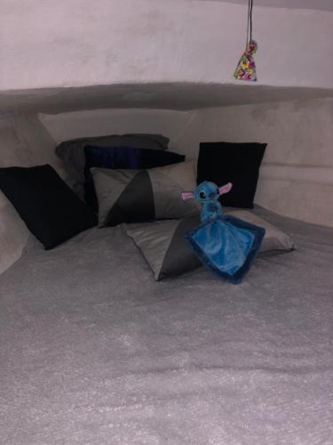 a stuffed cow sitting on a bed with pillows at Bateau aventure in Saint-Cyprien-Plage