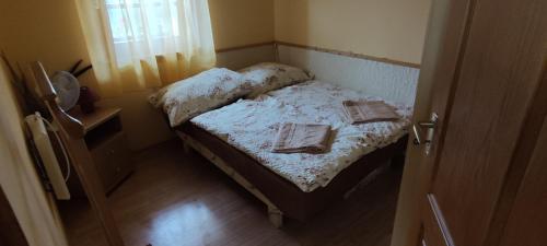 a small bedroom with a bed with two books on it at Szabó Pince Vendégház in Balatonederics