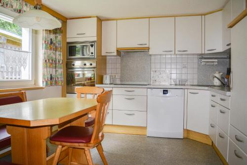 a kitchen with a wooden table and white cabinets at Villa Mondschein in Au im Bregenzerwald