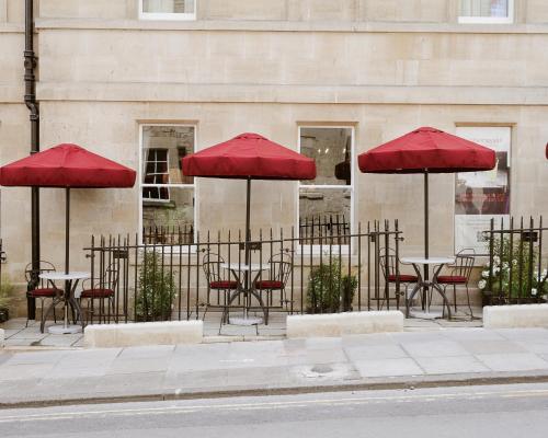 a group of tables and chairs with red umbrellas at Francis Hotel Bath in Bath