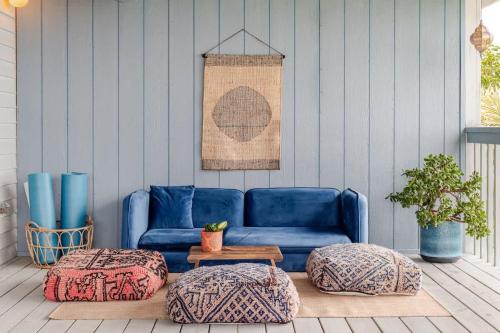 un divano blu seduto su una veranda con due pouf di Casa Grateful Hawaii a Kealakekua