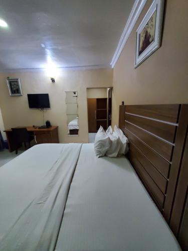 a bedroom with a large white bed and a desk at Romeo Suites & Apartment in Ipaja