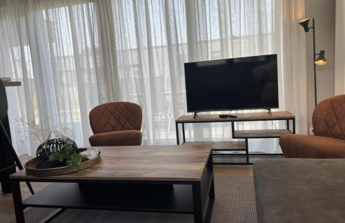 a living room with a flat screen tv and a table at Vakantiepark de Zeeuwse Parel - de Zeebries in Sint Maartensdijk