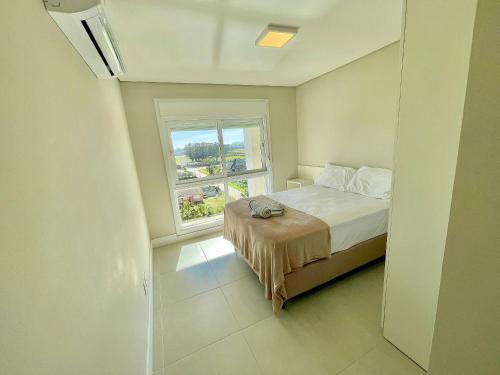 a small bedroom with a bed and a window at Atlântida Green Square - 607A in Xangri-lá