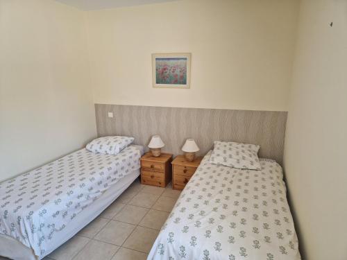 Un dormitorio con dos camas y dos mesitas de noche. en La combette, en Aubignan