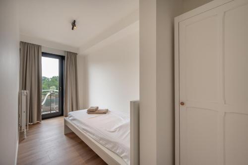ein weißes Schlafzimmer mit einem Bett und einem Fenster in der Unterkunft Appartement met 3 slaapkamers, terras en prachtig uitzicht in Knokke-Heist