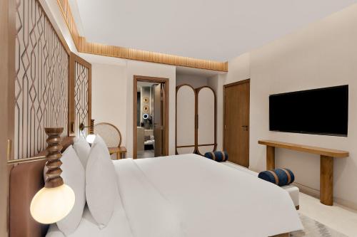 a bedroom with a white bed and a flat screen tv at Mercure Abu Dhabi Downtown in Abu Dhabi