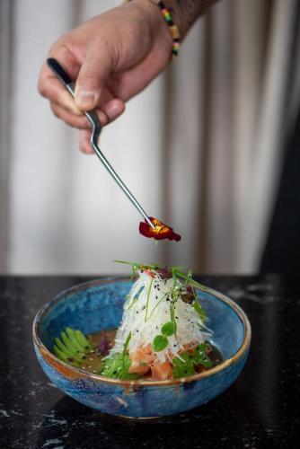 a person eating a bowl of food with a spoon at La Mansion Vi Vadi Hotel in Munich