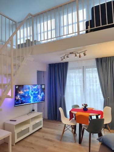 a living room with a tv and a table with chairs at Nahe Airport Ber Maisonettewohnung in Schönefeld