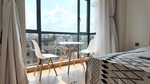 a bedroom with a bed and two chairs and a window at City Charm in Nairobi