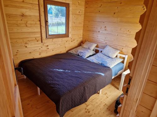 a bed in a log cabin with a window at Magiczny domek in Drzewoszewo