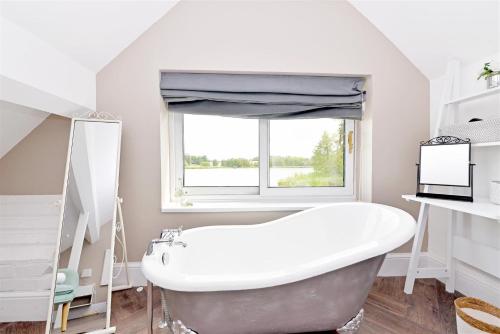 a bathroom with a white tub and a window at The Boathouse in Lichfield