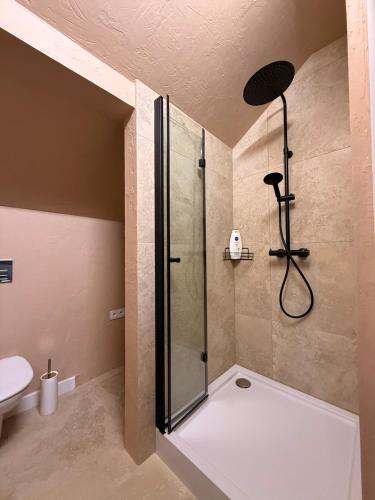 a bathroom with a shower with a glass door at Apartament pod miastem in Lanckorona
