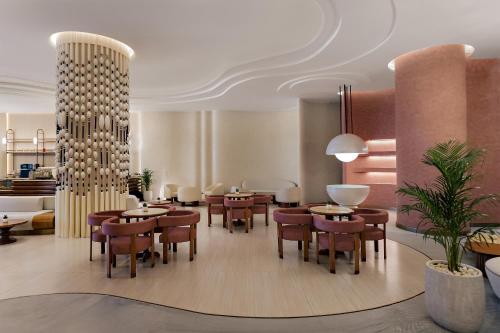 a restaurant with tables and chairs in a room at Mercure Abu Dhabi Downtown in Abu Dhabi