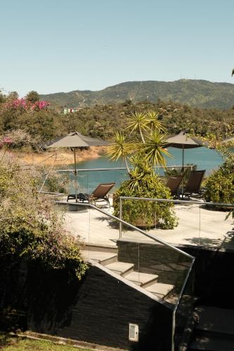 a group of chairs and umbrellas next to a body of water at Tau House in Guatapé
