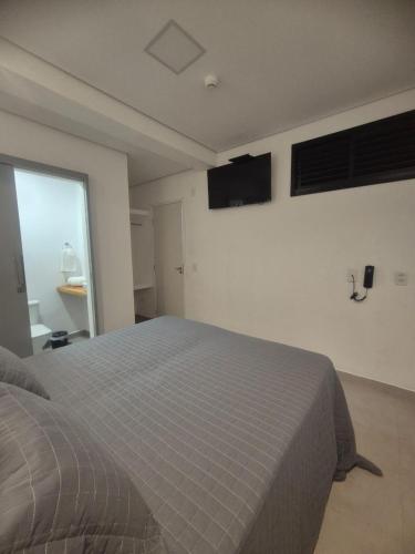 a bedroom with a bed and a television on the wall at Fortunato Hotel in Bragança Paulista