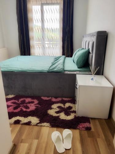 una camera da letto con un letto con una finestra e un tappeto di AriApartament a Kosovska Mitrovica