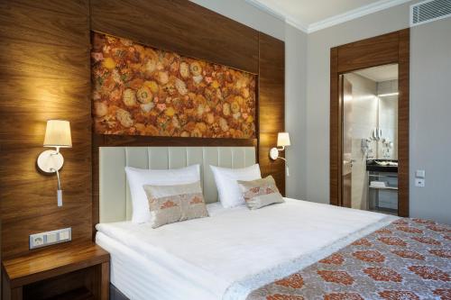 a bedroom with a large bed with a painting on the wall at ARDEN PALACE Medical Resort & SPA in Satanov