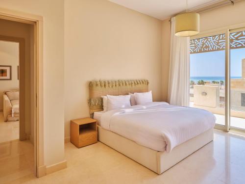 a white bedroom with a bed and a large window at Boutique Residence Mangroovy-Lemon Spaces Gouna in Hurghada