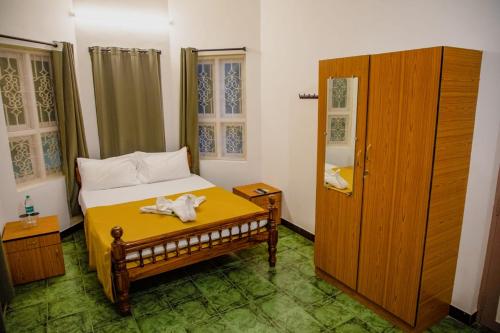a small bedroom with a bed and a wooden cabinet at Maison Blanche DK in Puducherry
