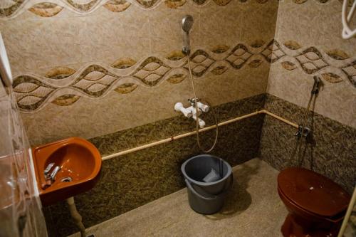 a bathroom with a toilet and a sink and a trash can at Maison Blanche DK in Puducherry