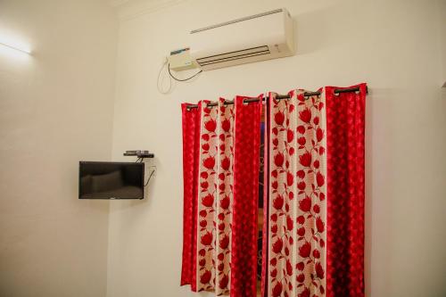 a room with two red curtains and a air conditioner at Maison Blanche DK in Puducherry