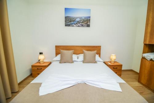 a bedroom with a large white bed with two lamps at The Blue House in Široka