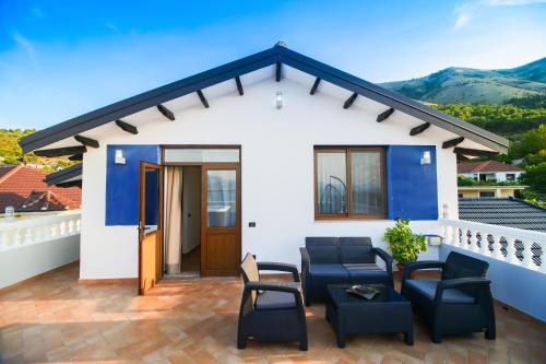 a small white house with a patio with chairs at The Blue House in Široka