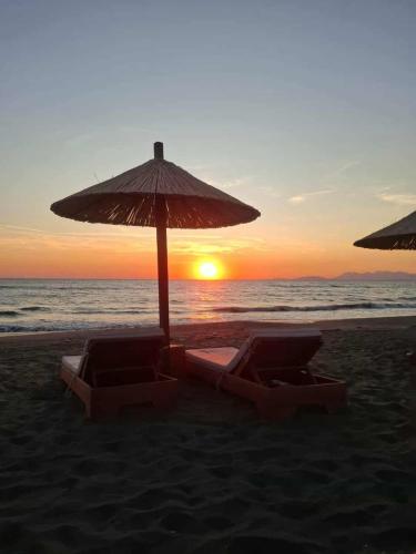 two beach chairs and an umbrella on the beach at Green 2-bedroom apartment beach in Tale