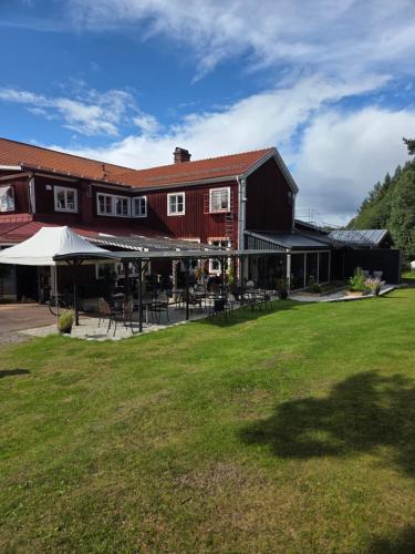 a building with tables and chairs in a yard at Sjugare Gård Bed & Breakfast in Leksand