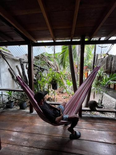 a man sitting in a hammock on a porch at Casa Kresala, Surf House in Zorritos