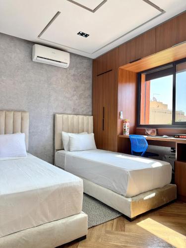 two beds in a hotel room with a desk and a desk at Villa Palmeraie Luxe, 7 min de Geliz & Piscine Privée in Marrakech