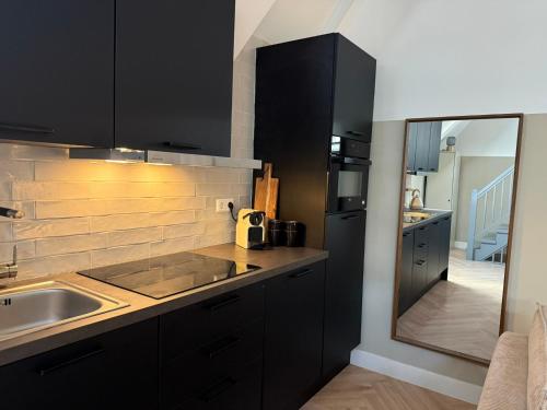 a kitchen with black cabinets and a sink at Naest - Authentic Escapes Old Town Villa Nijmegen in Nijmegen