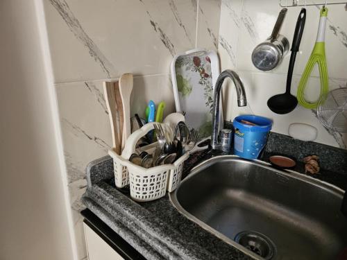 eine Küchenspüle mit einem Korb voller Küchenutensilien in der Unterkunft Santorini Resort apartment in Dawwār Shindī Fannūsh