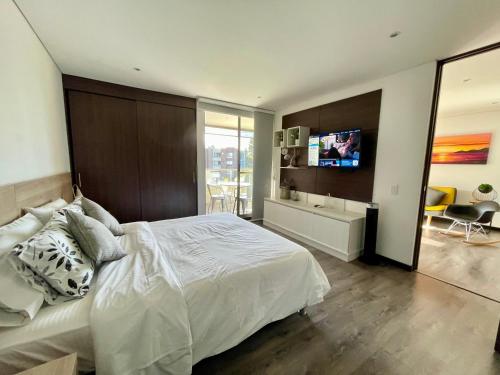 una camera da letto con un grande letto bianco e una televisione di aparta hotel campestre luxury en llanogrande 10 minutos aeropuerto a Rionegro