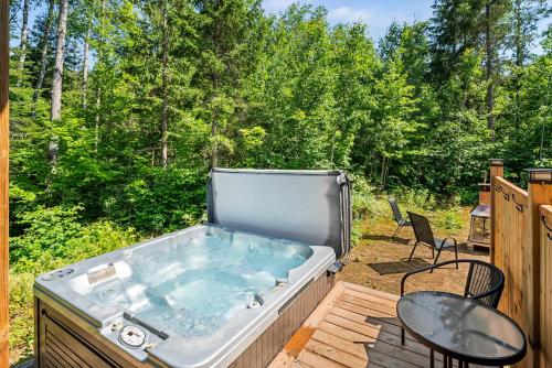 a hot tub on a deck with a table and chairs at Spa Nature & Riverside Escape - Ecureuil Roux in Trois Rives