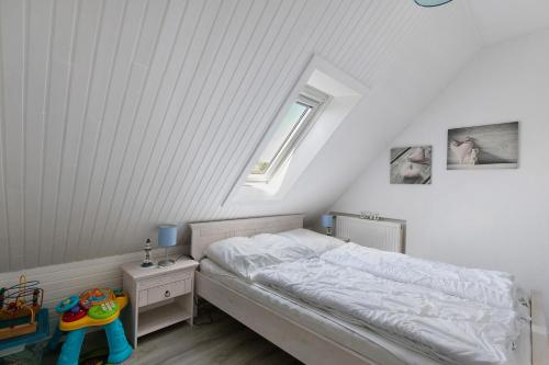 une chambre blanche avec un lit et une fenêtre dans l'établissement Fewo Küstkieker, à Sankt Peter-Ording