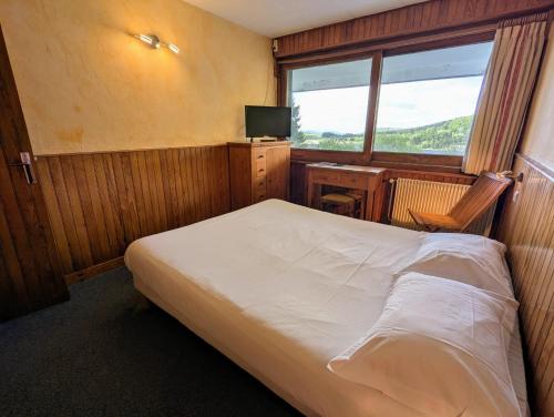 a bedroom with a bed and a desk and a window at Gergovia in Super Besse