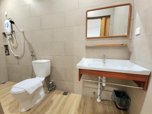 a bathroom with a toilet and a sink and a mirror at Luna Suites Comfort Stay in Lahad Datu in Lahad Datu