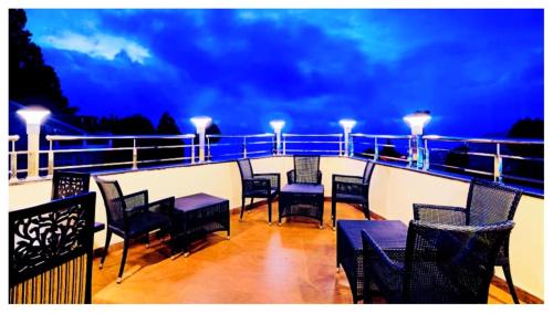 a balcony with tables and chairs on a ship at night at Hotel Zambala Retreat & Spa Darjeeling in Darjeeling