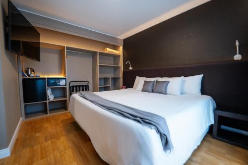 ein Schlafzimmer mit einem großen weißen Bett und einem Fernseher in der Unterkunft Amérian Córdoba in Cordoba