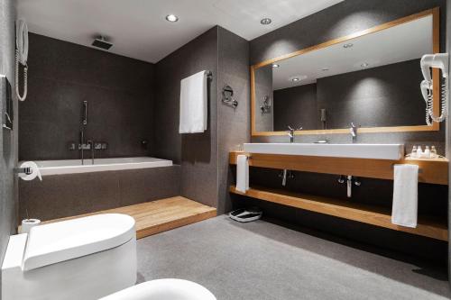 a bathroom with a tub and a toilet and a sink at Holiday Inn - Tbilisi by IHG in Tbilisi City
