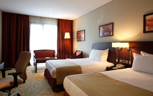 a hotel room with two beds and a chair at Holiday Inn Olaya by IHG in Riyadh