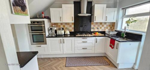 a white kitchen with white cabinets and appliances at Home from Home near the beach in Port Talbot